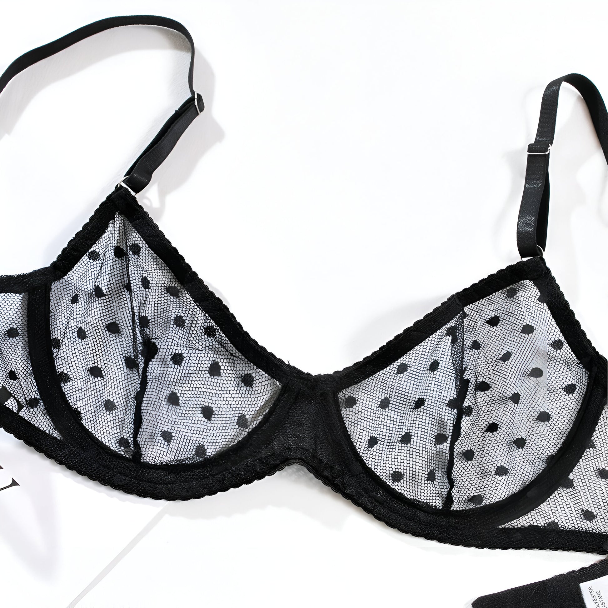 Black bra with mesh panels featuring a polka dot pattern on a white background