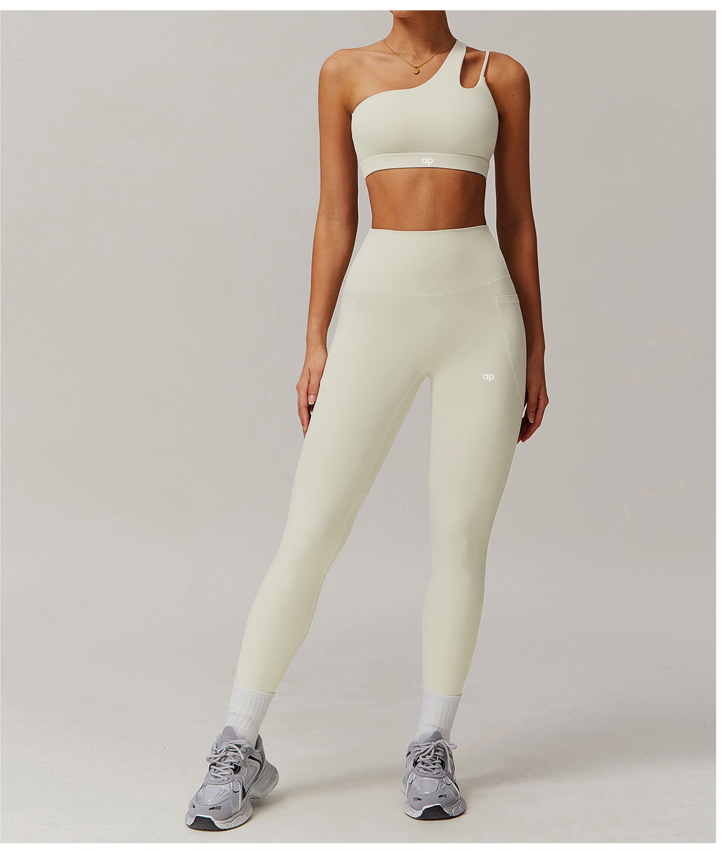 Person wearing a light-colored sports bra and leggings set on a plain background