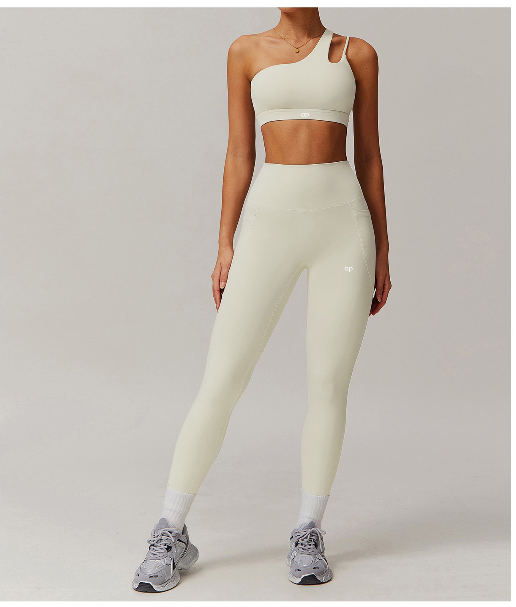 Person wearing a light-colored sports bra and leggings set on a plain background